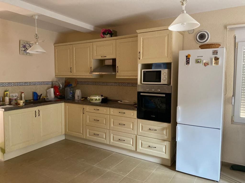 Cozy bright kitchen in a house in Dobra Voda, Montenegro: classic cabinetry, built-in appliances, and tiled flooring.
