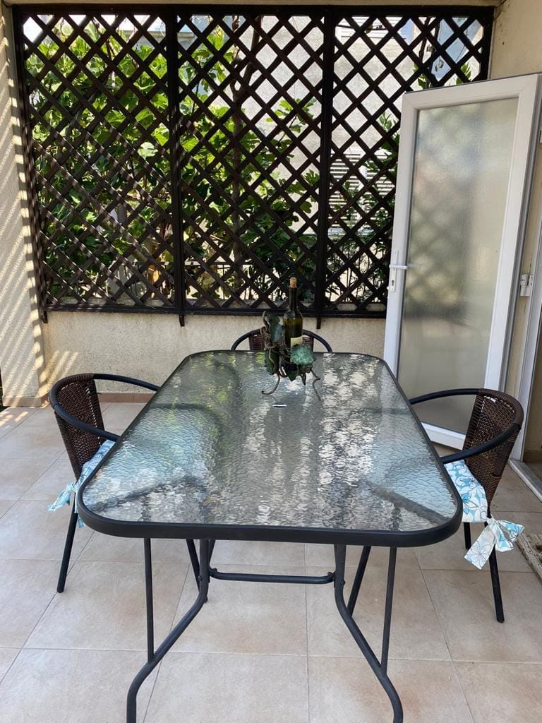 Cozy terrace with dining area in a house, Dobra Voda, Montenegro: glass table, wicker chairs, and decor.