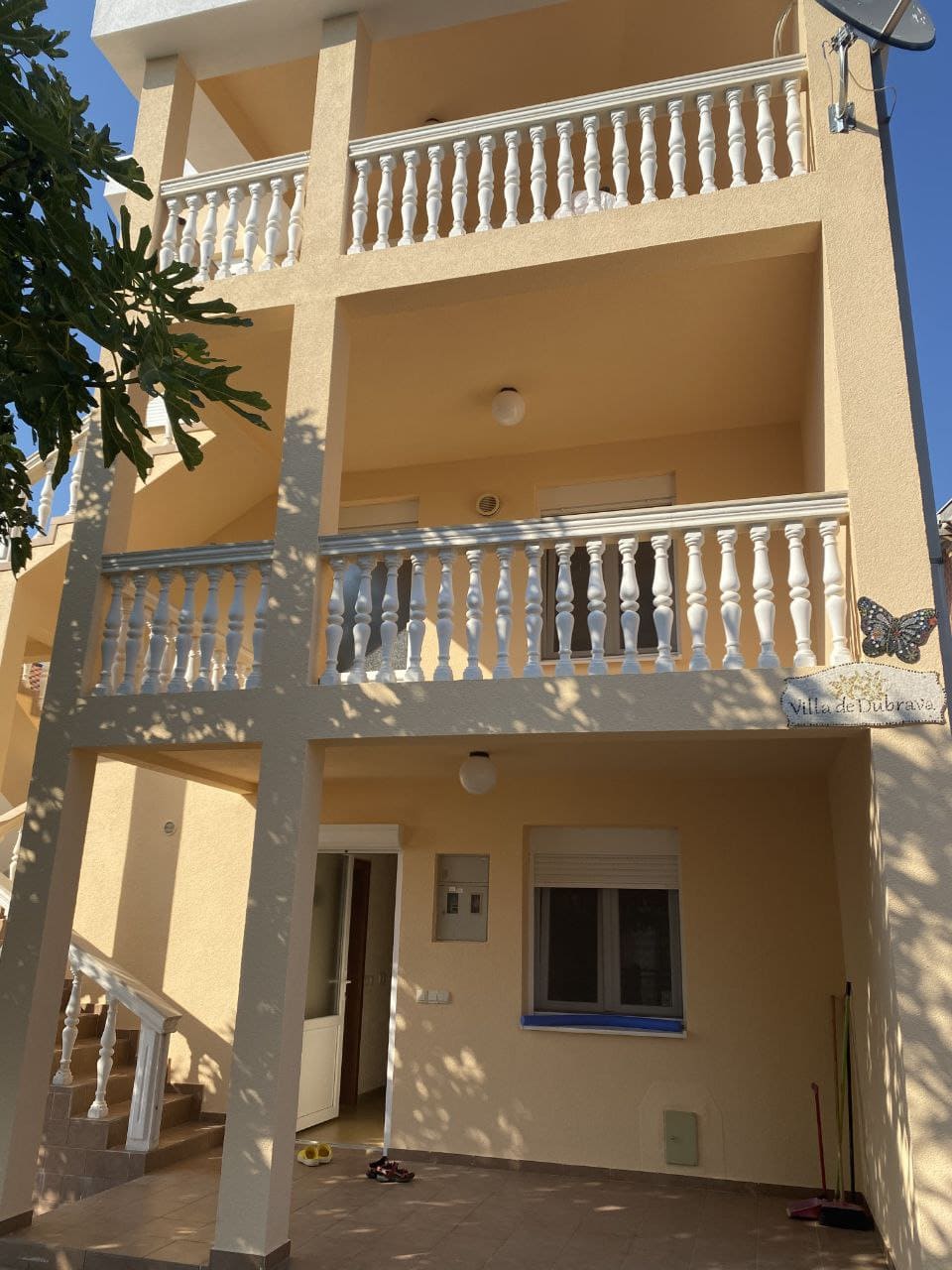 Facade of the three-story Villa de Dubrava in Dobra Voda, Montenegro, with open terraces and white balustrades.