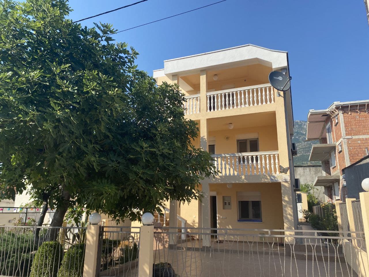 Three-story villa with balconies and a garden in Dobra Voda, Montenegro: front view of the house with a fenced property.