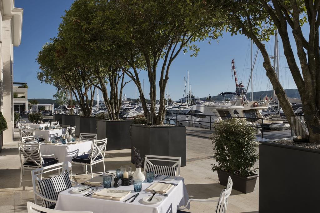 Summer restaurant terrace overlooking the Porto Montenegro yacht marina, Tivat, Montenegro, tables on the waterfront.