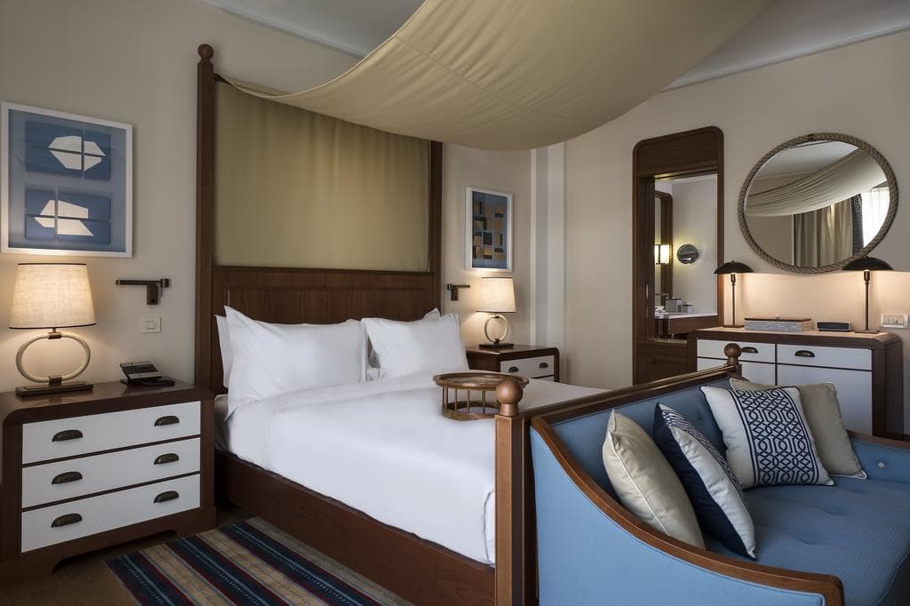 Bedroom interior in a studio in Tivat, Montenegro: a double canopy bed, a blue sofa, and stylish furniture.
