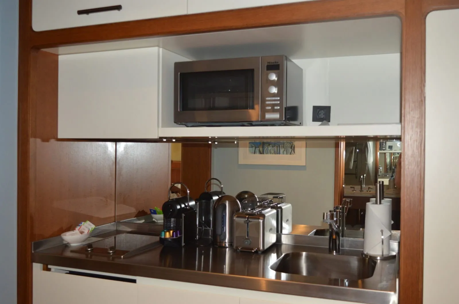 Kitchenette with stainless steel counter, microwave, toaster, and coffee machine set within a wooden frame structure.