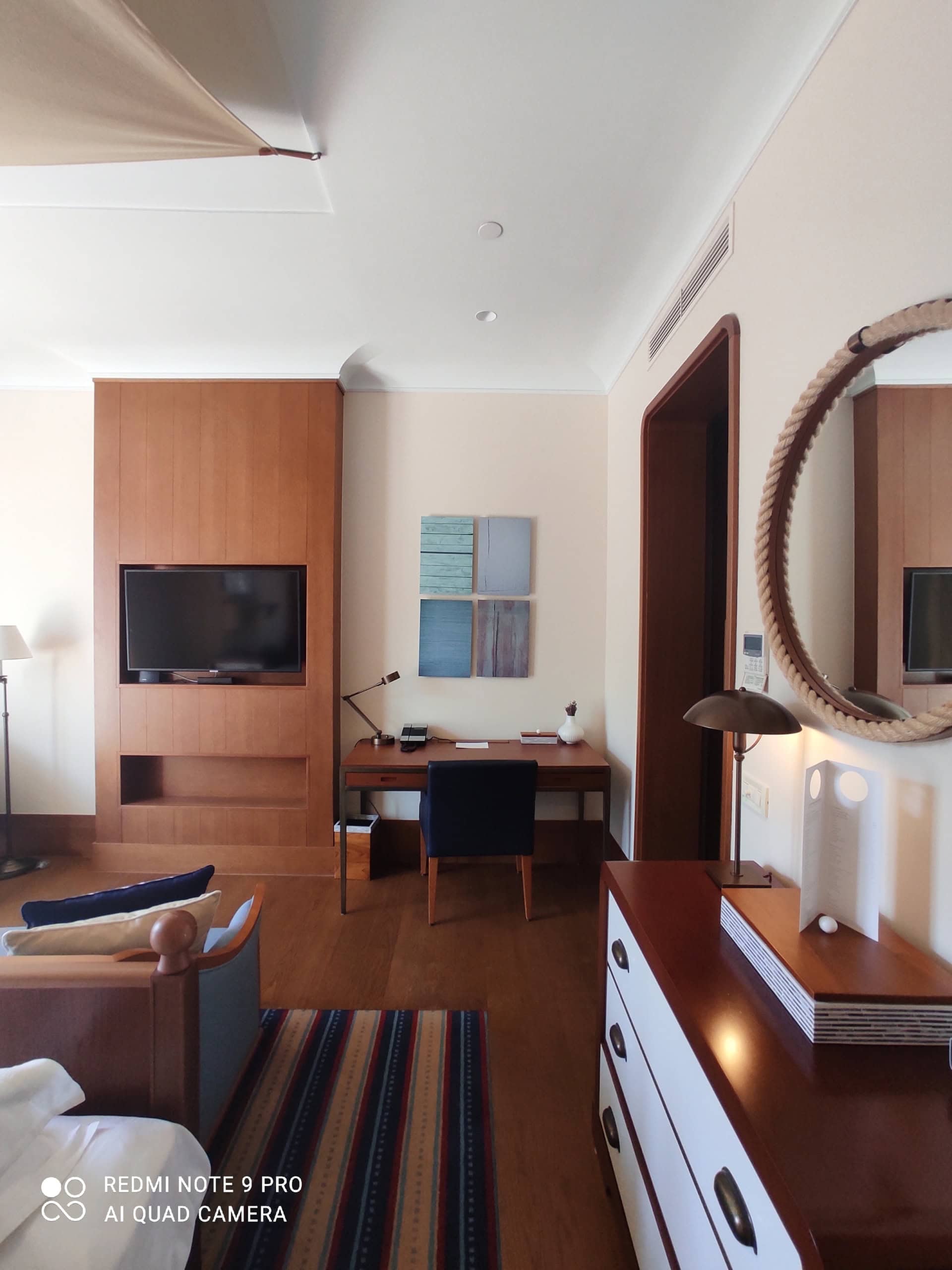 Interior of a modern bedroom in an apartment in Tivat, Montenegro: wooden furniture, a desk, and a round mirror.