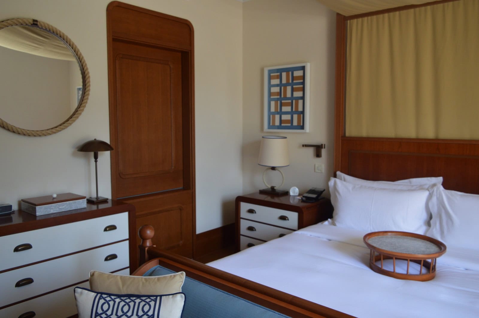 Bedroom interior in an apartment in Tivat, Montenegro: a double bed, wooden furniture, and a round mirror.