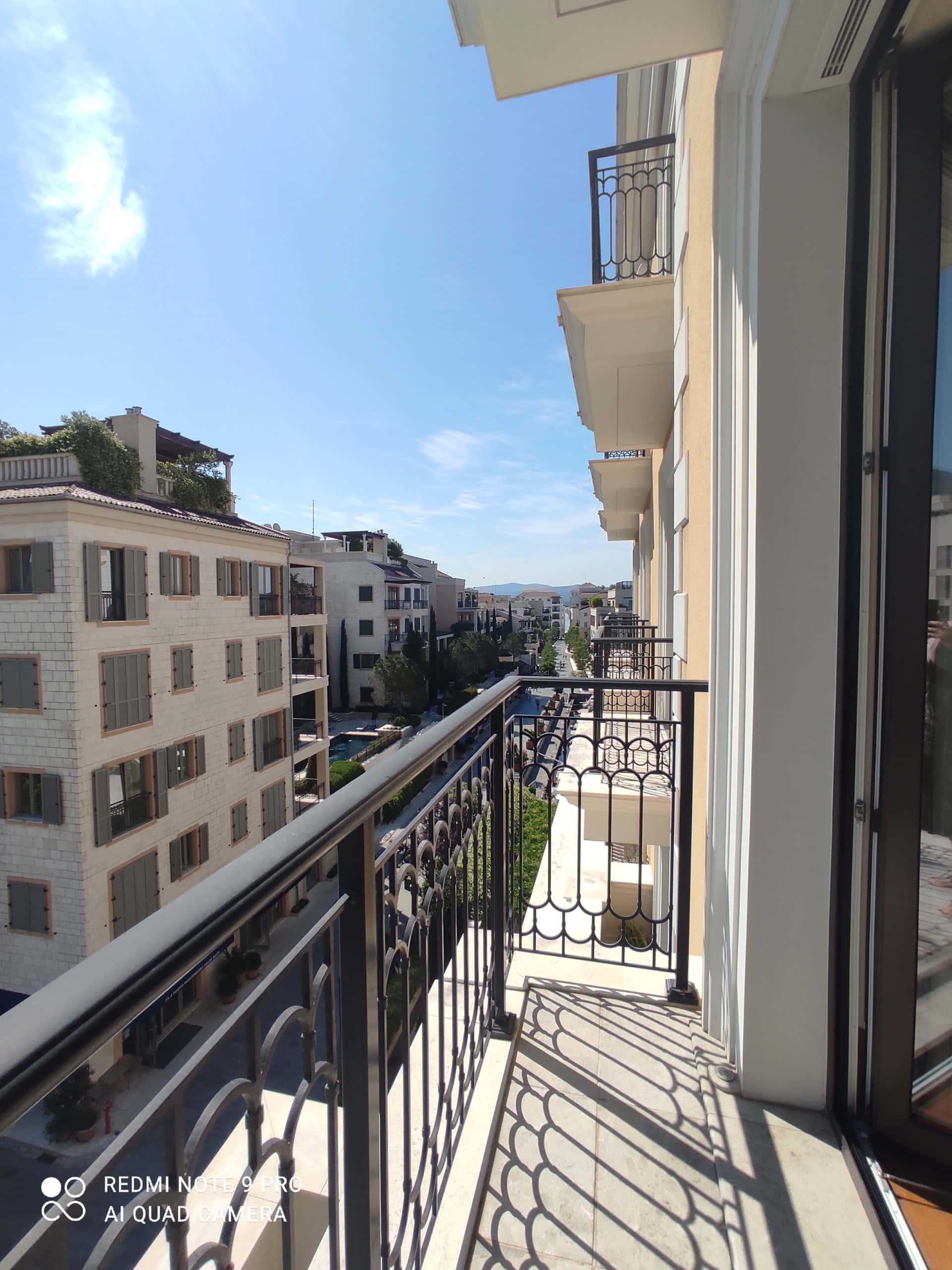View from the apartment balcony in Tivat, Montenegro: wrought-iron railing and a panoramic view of the residential complex with a swimming pool.