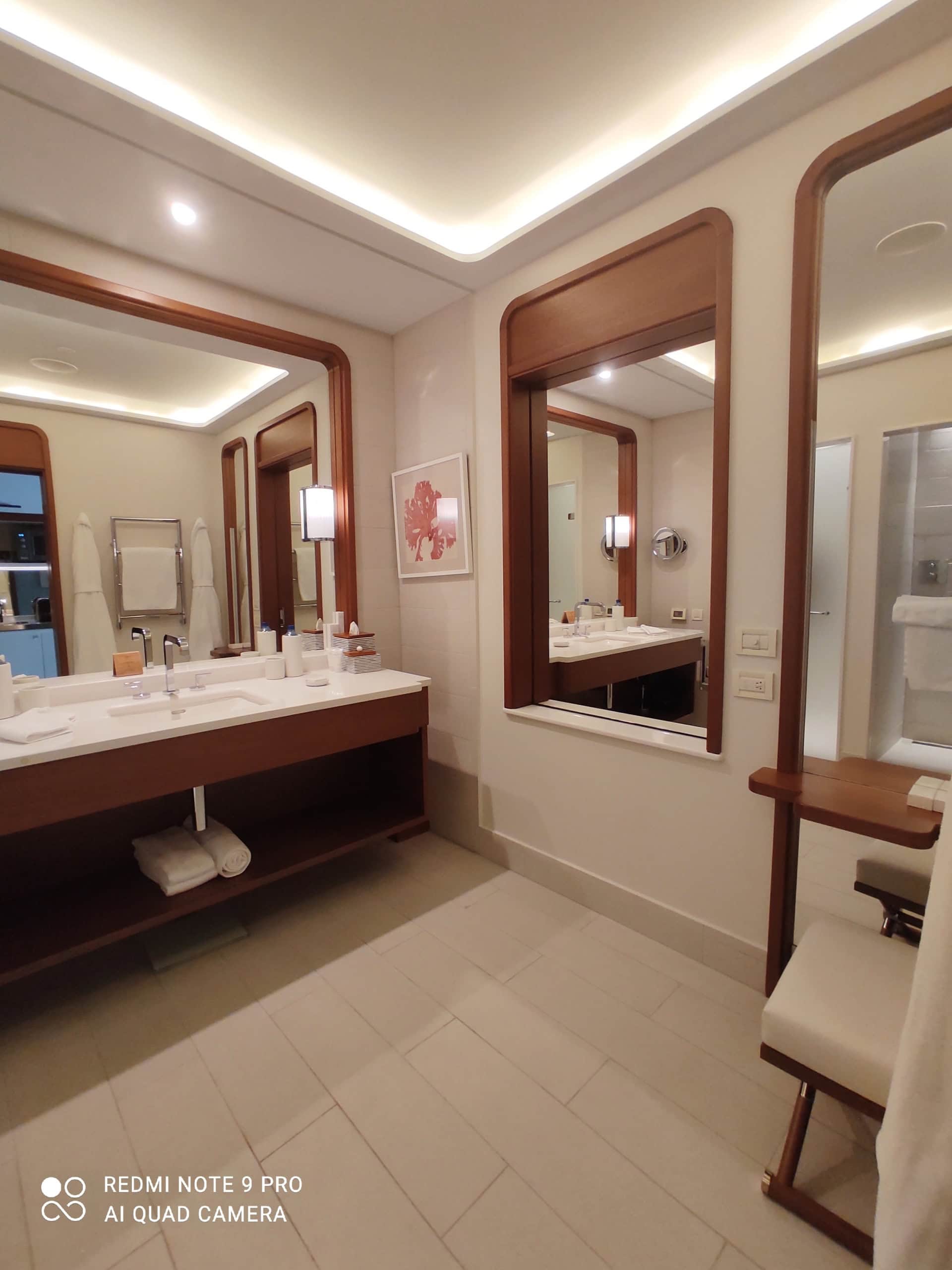 Modern bathroom in an apartment in Tivat, Montenegro: stylish wooden furniture, large mirrors, and lighting.