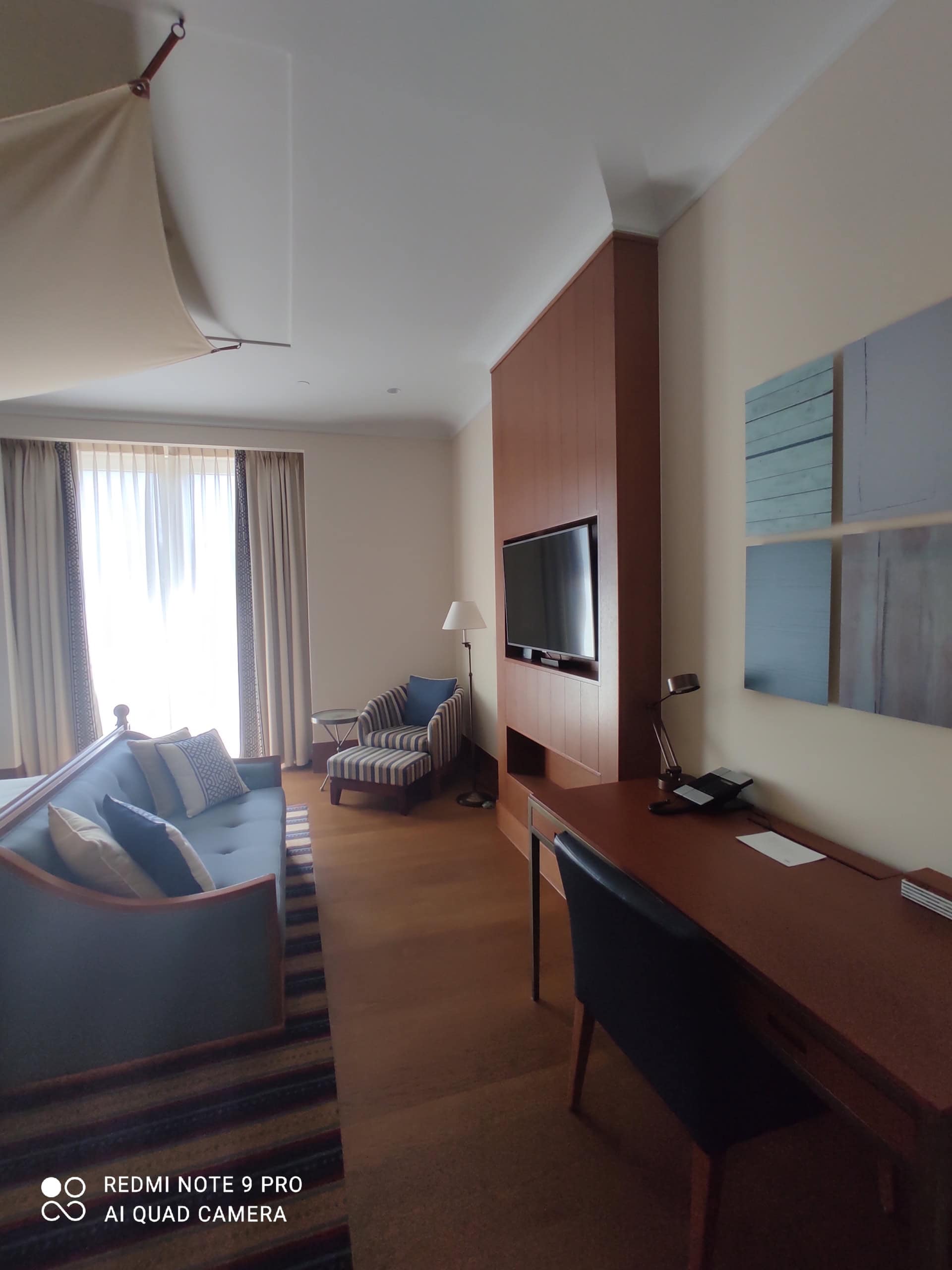 Living room interior in a studio in Tivat, Montenegro: a soft sofa, workspace, TV, and stylish wood finishes.