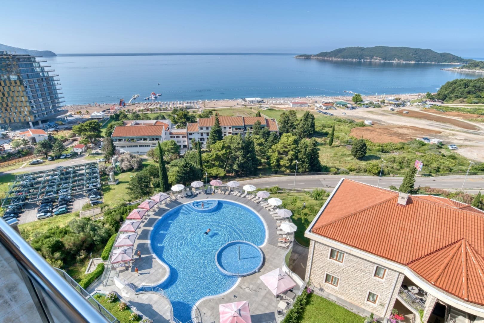 View from the penthouse balcony in Bečići, Montenegro: outdoor swimming pool, beach, and panoramic view of the Adriatic Sea.