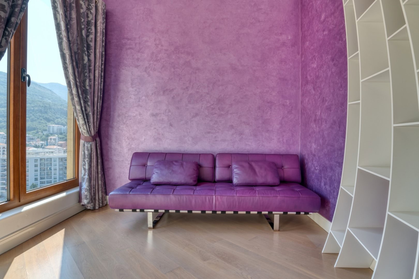 Living room with a purple sofa and panoramic mountain views in a penthouse, Becici, Montenegro.