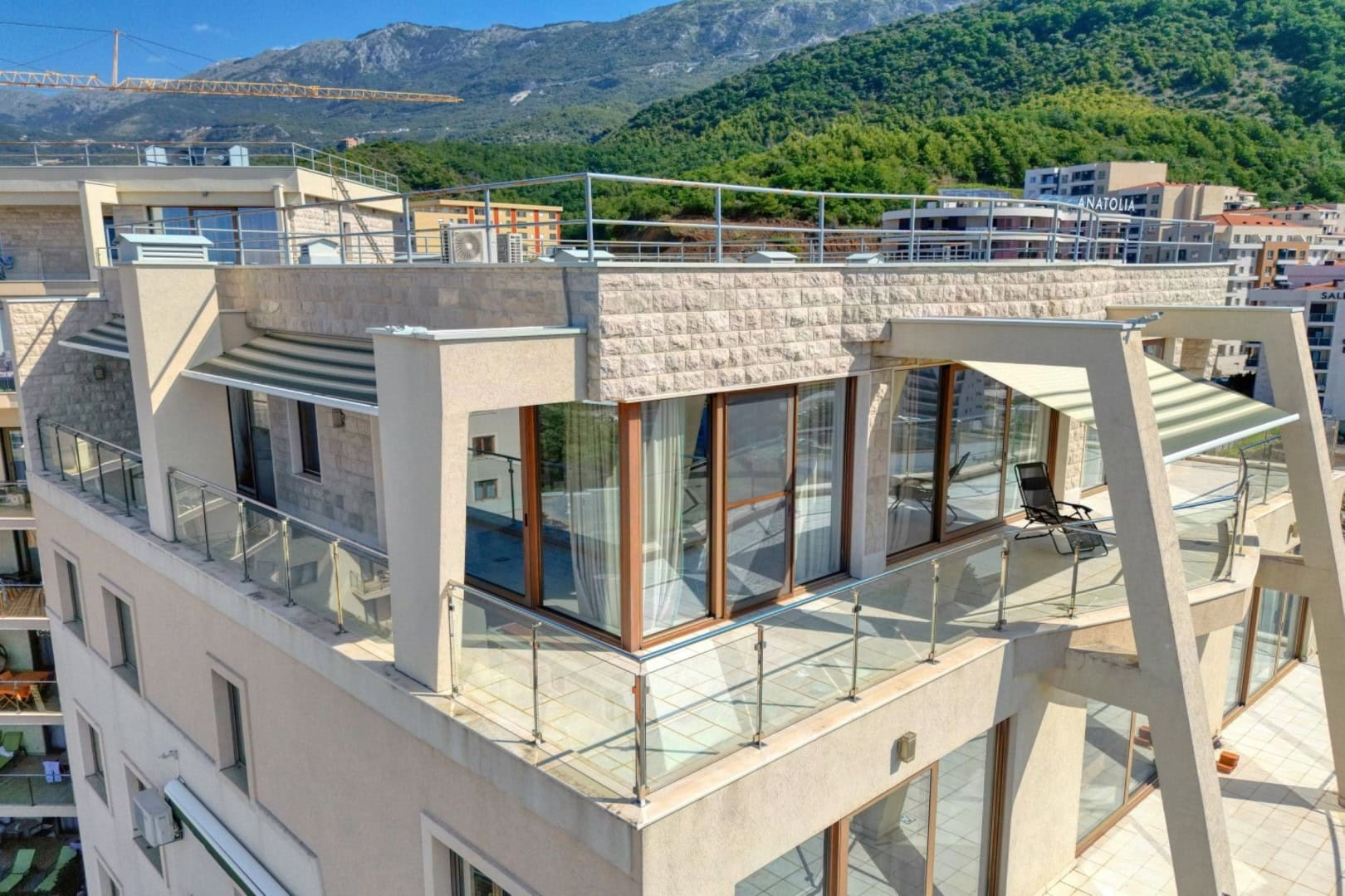 Penthouse with a panoramic terrace and mountain views in Bečići, Montenegro: modern finishes and glass railings.