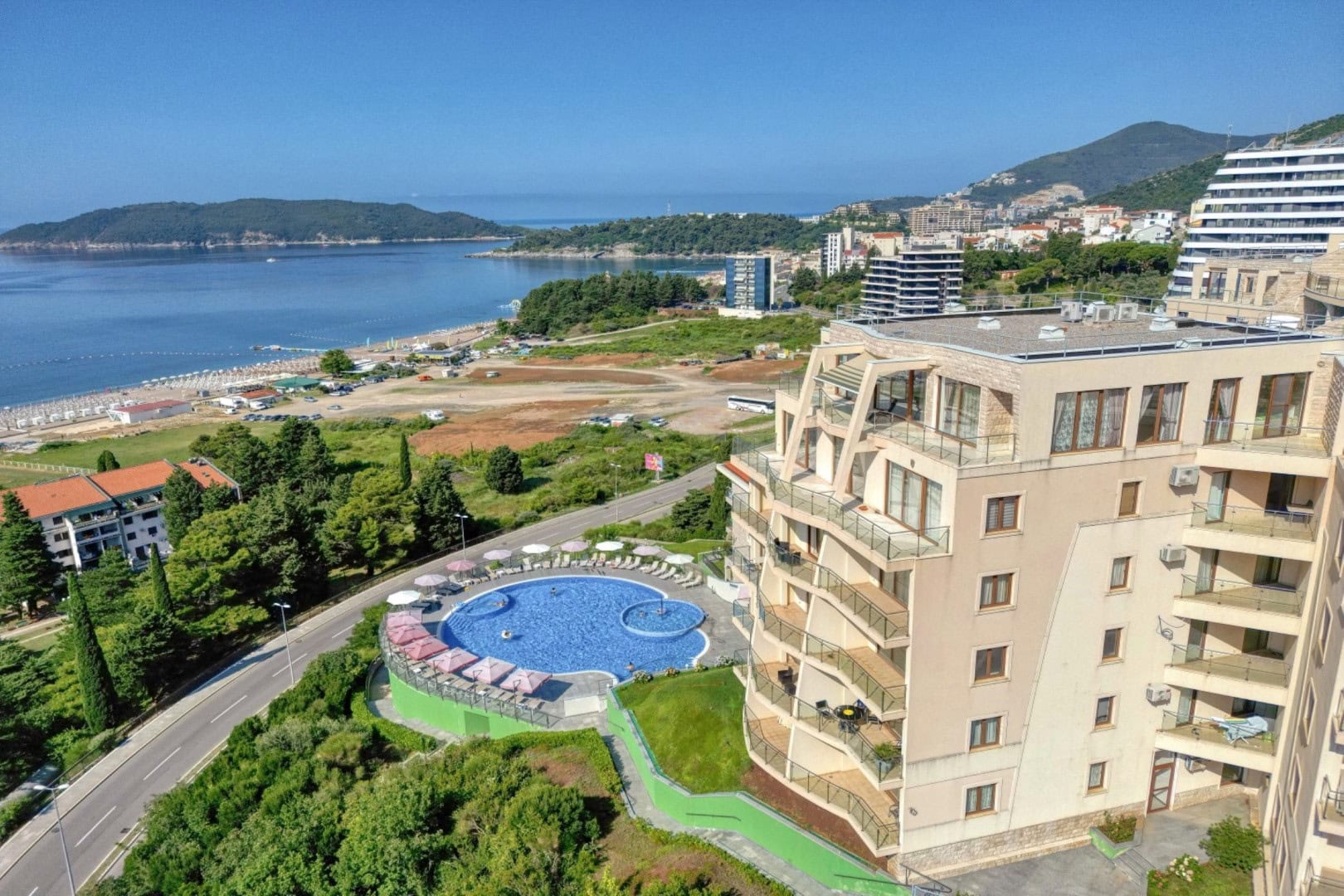 Aerial view of a residential complex with a swimming pool, beach, and the sea in Bečići, Montenegro. Penthouse with a panoramic view of the coast.