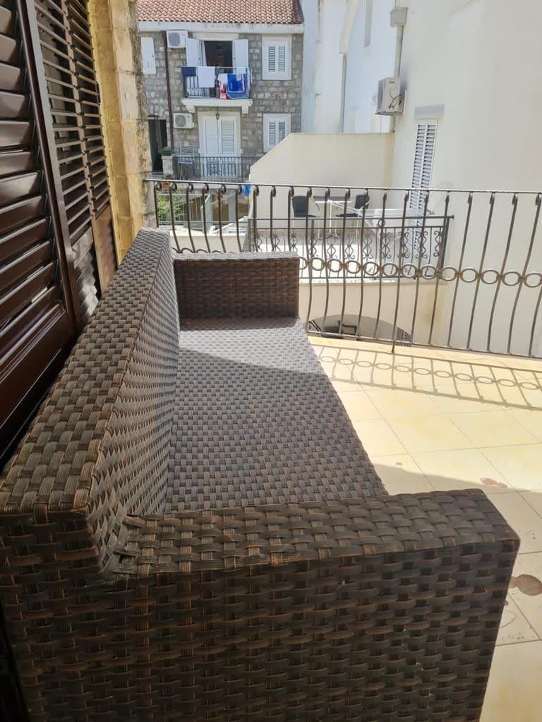Wicker sofa on the balcony of an apartment in Petrovac, Montenegro, overlooking the city’s historic architecture.