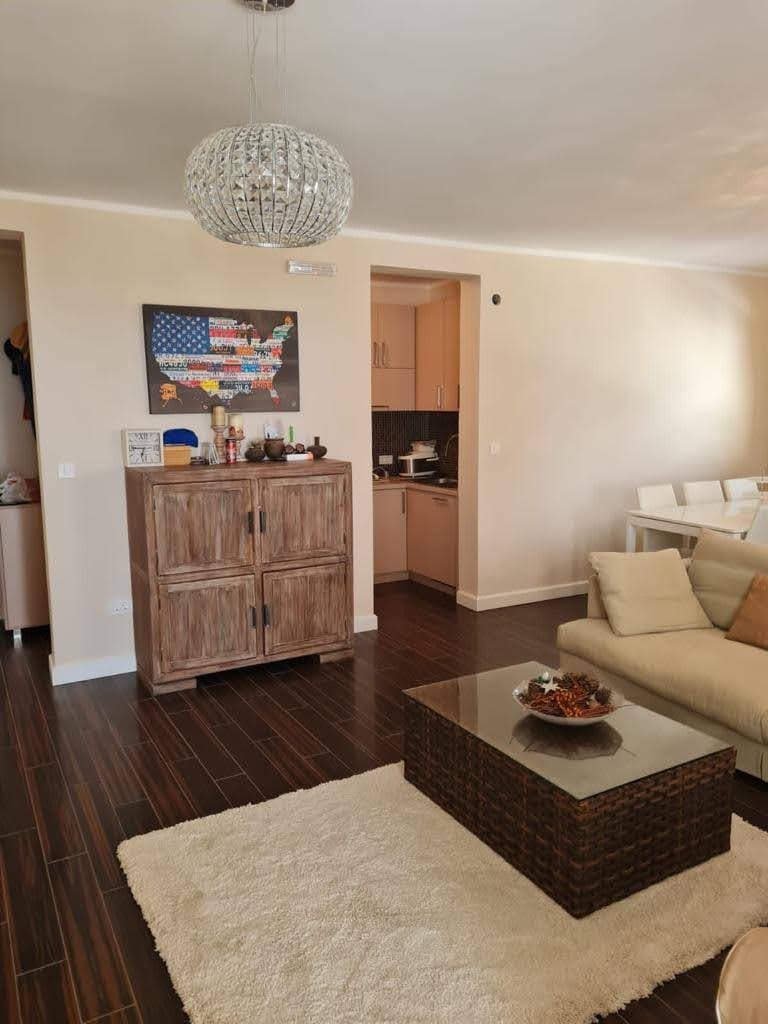 Living room with dark flooring, a beige sofa, and a wooden cabinet in an apartment, Petrovac, Montenegro.