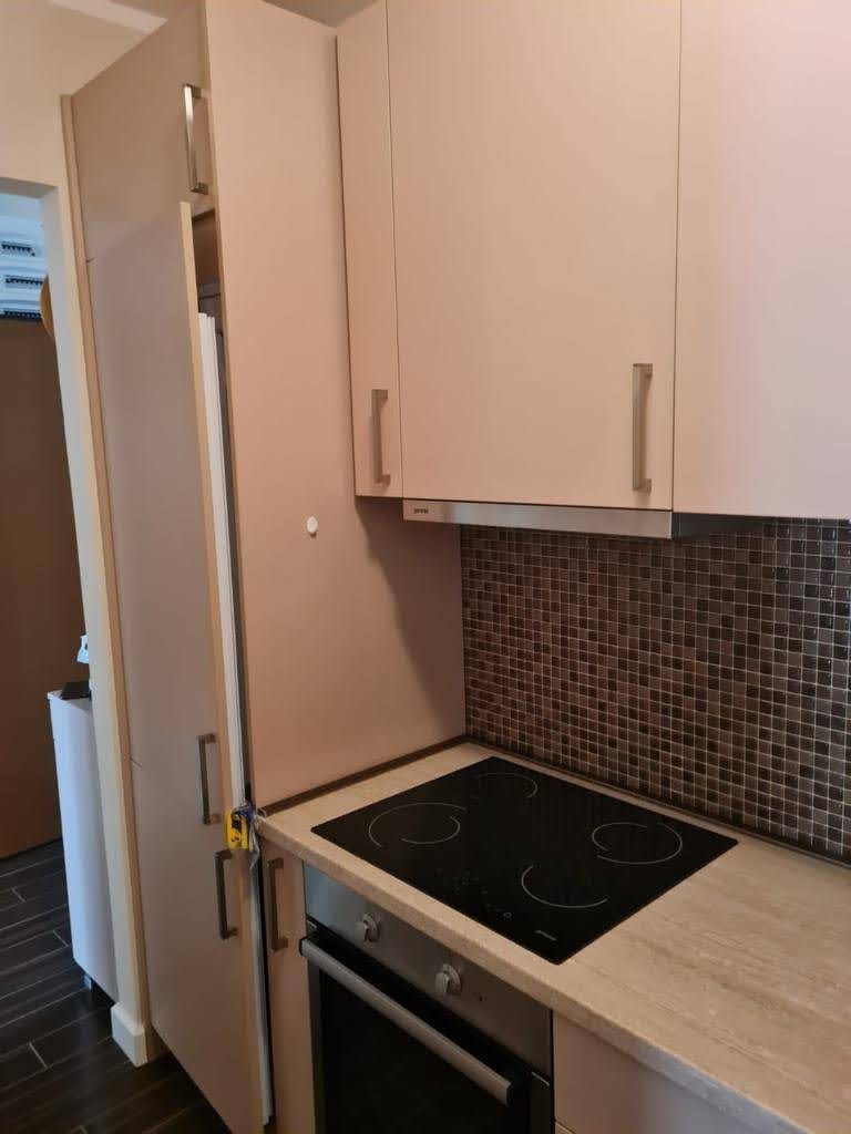 Modern kitchen in an apartment in Petrovac, Montenegro: beige cabinets, built-in cooktop, and mosaic backsplash.