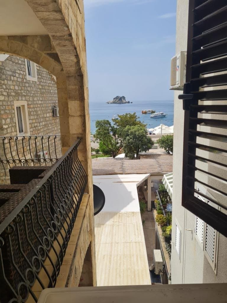 View from the balcony of a stone house of the sea and island in Petrovac, Montenegro: wrought-iron railings and a seascape.