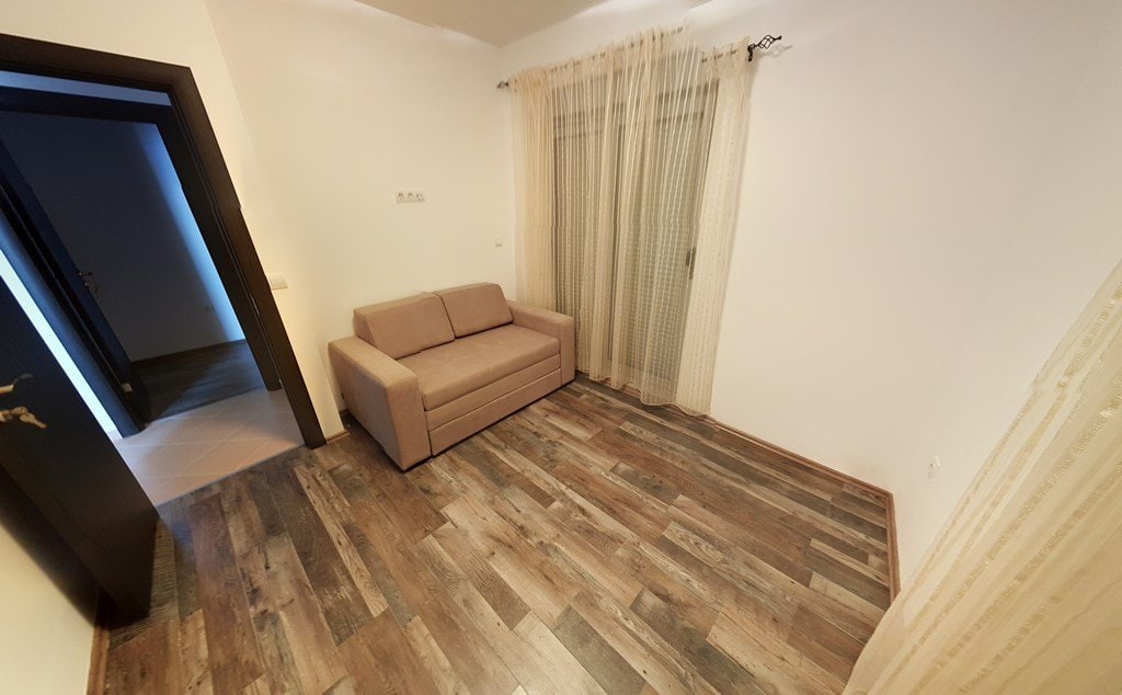 Bright living room with a beige sofa and laminate flooring in an apartment for sale in Budva, Montenegro.