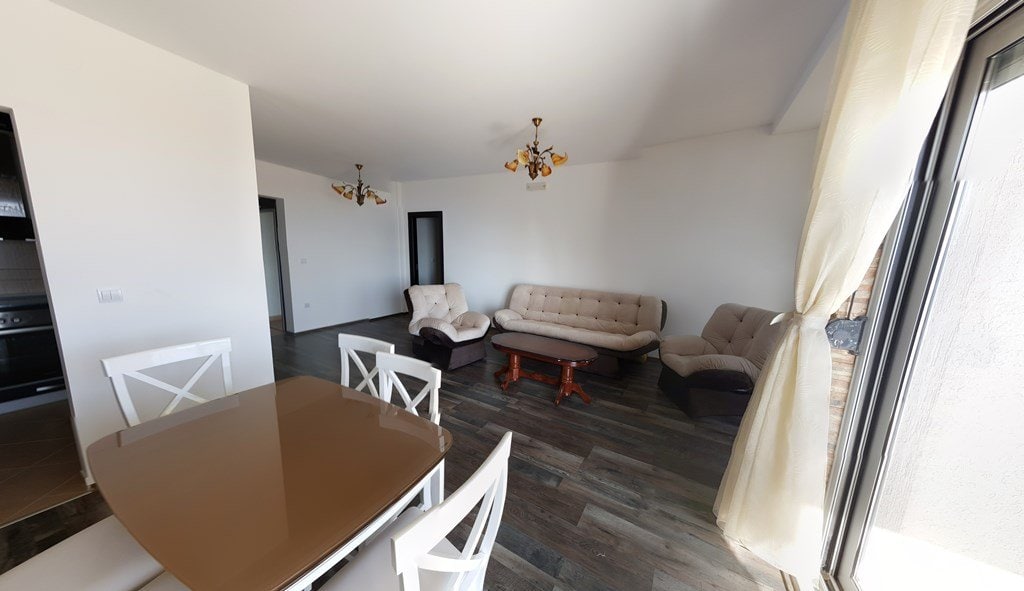 Bright living room with soft seating and a dining area in an apartment in Budva, Montenegro. Modern interior with laminate flooring.