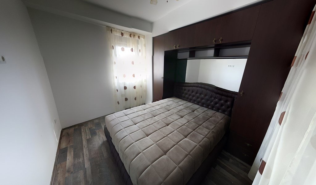 Bedroom in an apartment in Budva, Montenegro: double bed, built-in mirrored wardrobe, and wood-look laminate flooring.