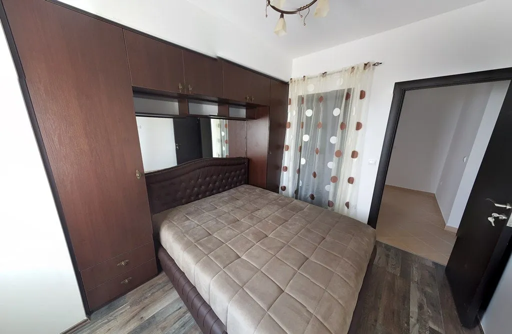 Bedroom featuring a double bed with a tufted headboard and a large dark wood wardrobe unit.