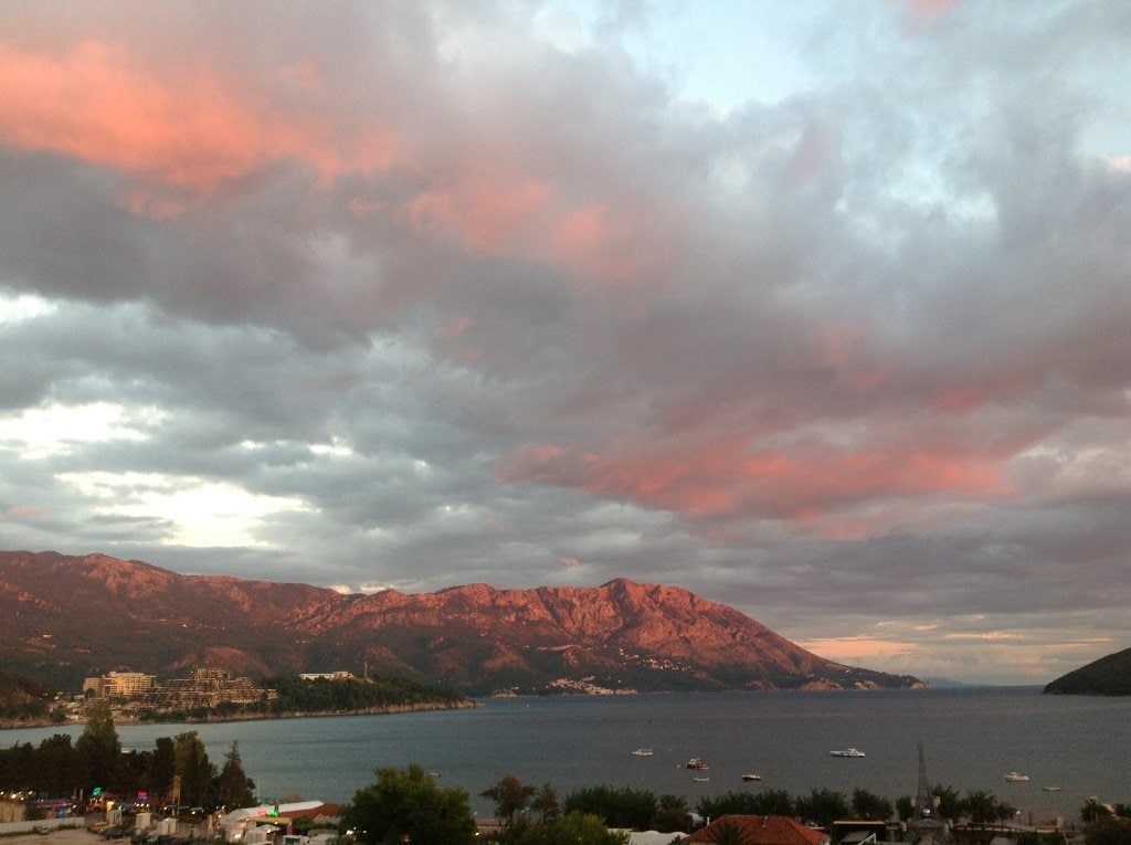 Panoramic view of the sea and mountains in Budva, Montenegro: sunset sky over the coastline and resort area of the city.