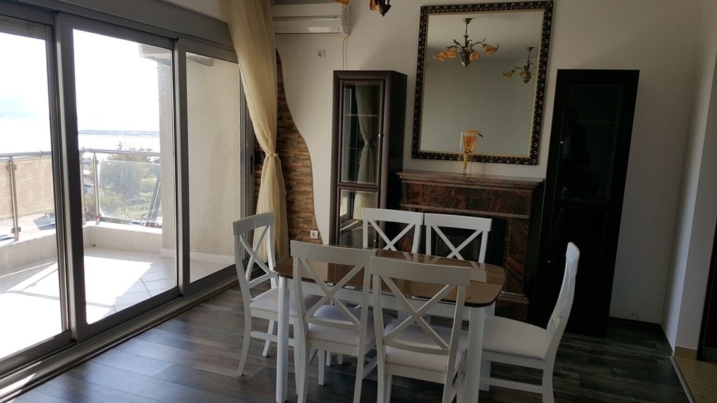 Living room with dining area, fireplace, and panoramic sea view in an apartment in Budva, Montenegro.