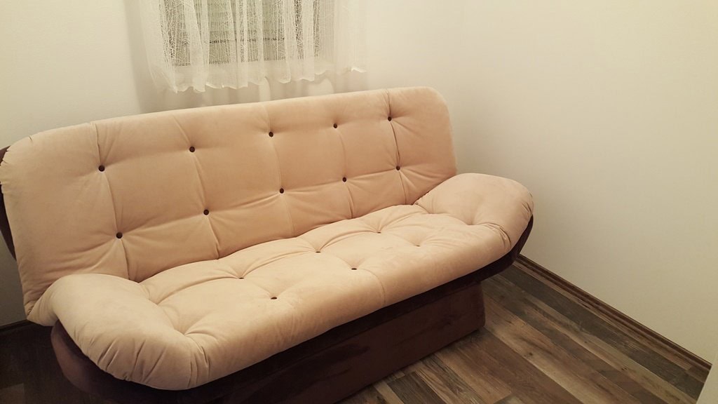 Light-colored sofa in the living room of an apartment in Budva, Montenegro: interior with laminate flooring and white walls.
