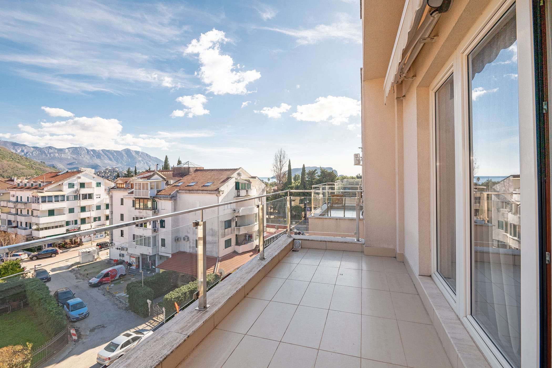 Spacious balcony with panoramic views of the city, mountains, and sea in an apartment in Budva, Montenegro.