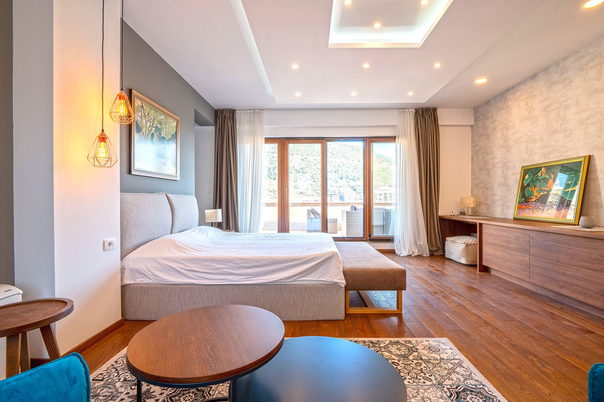 Modern bedroom in a duplex in Budva, Montenegro: double bed, wooden floor, and access to a terrace with a view.