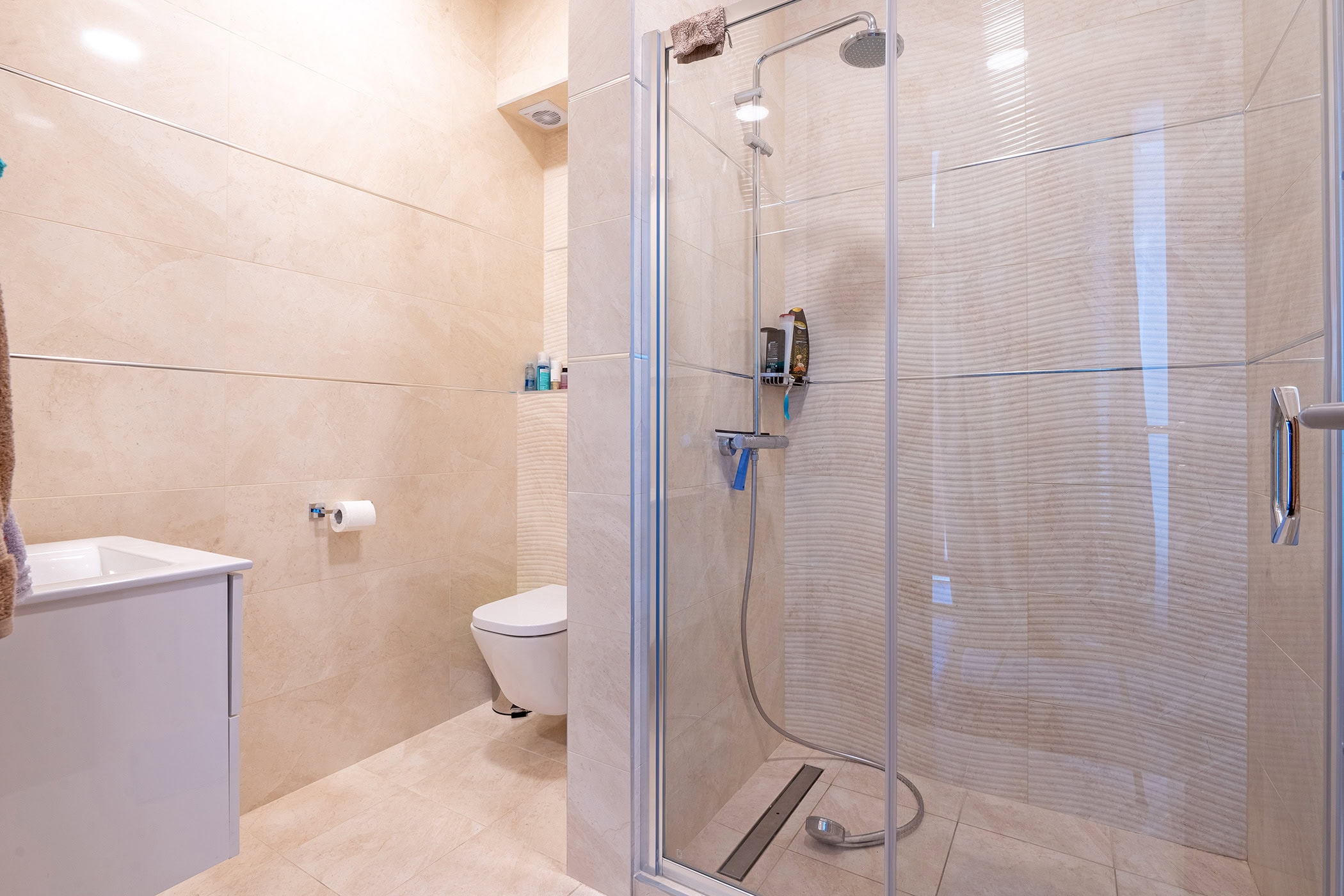 Modern bathroom in an apartment in Budva, Montenegro: shower cabin, light-colored tiles, and sanitary ware.