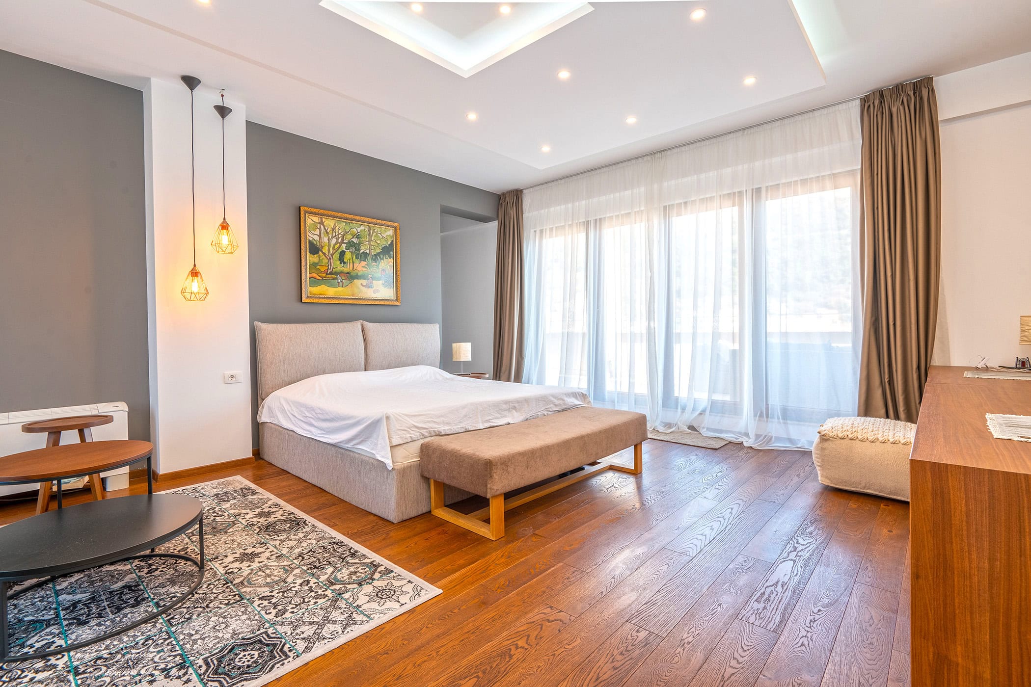 Modern bedroom in an apartment in Budva, Montenegro: a double bed, panoramic windows, and stylish interior.