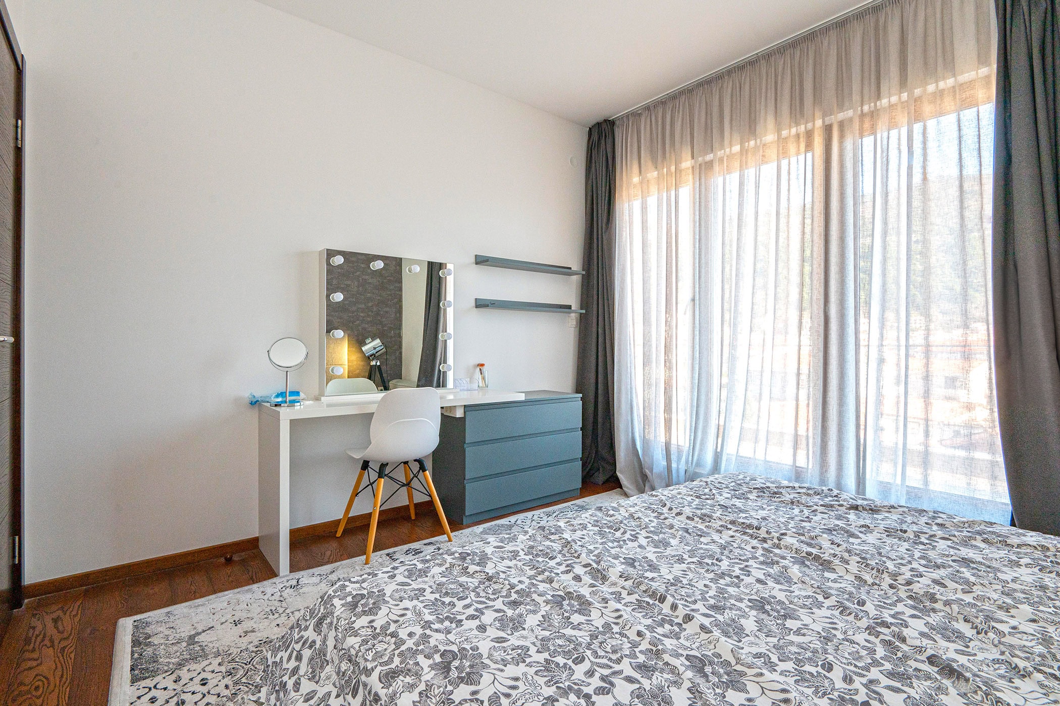 Modern bedroom with a vanity table and a panoramic window in an apartment in Budva, Montenegro.