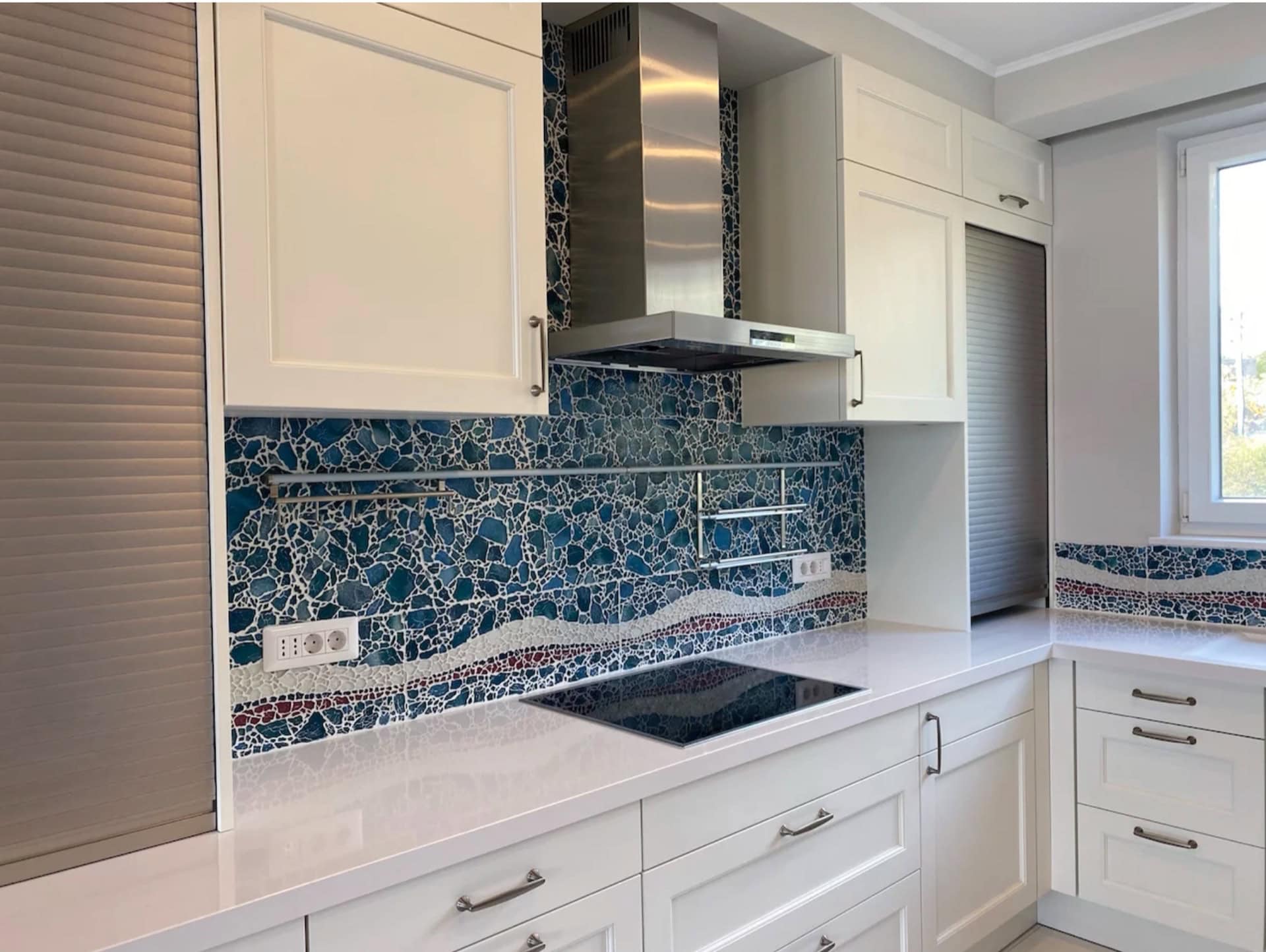 Modern white kitchen with a mosaic backsplash in an apartment in Bečići, Montenegro. Built-in appliances and a bright interior.