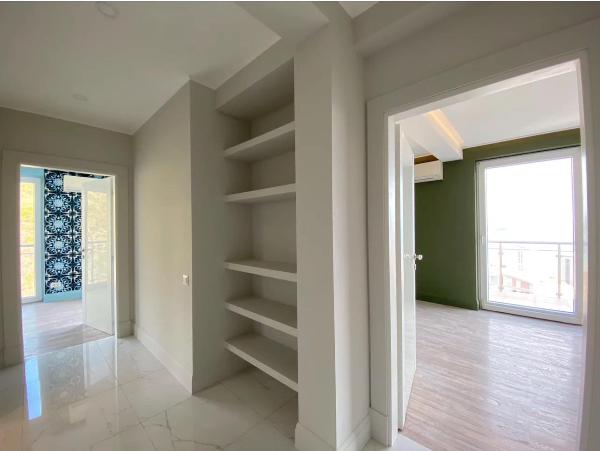 Apartment interior in Bečići, Montenegro: a bright hallway with built-in shelves and access to rooms with panoramic windows.