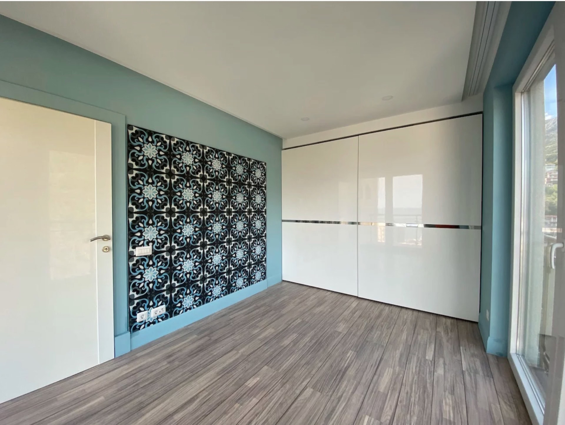 Bright bedroom with a white sliding wardrobe and an accent wall in an apartment in Bečići, Montenegro. Modern interior.