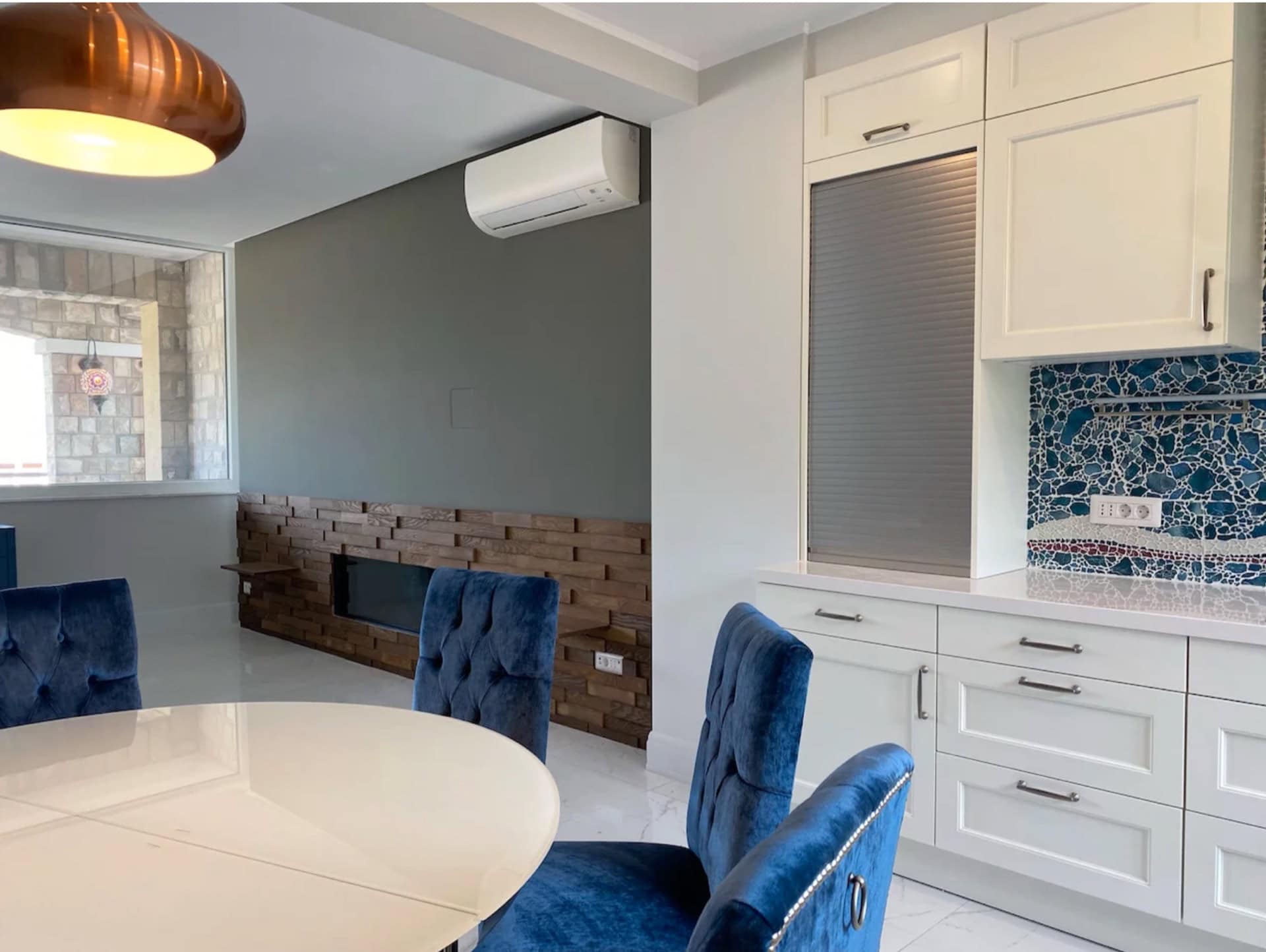 Modern kitchen in an apartment in Bečići, Montenegro: white fronts, blue velvet chairs, and wood finishes.