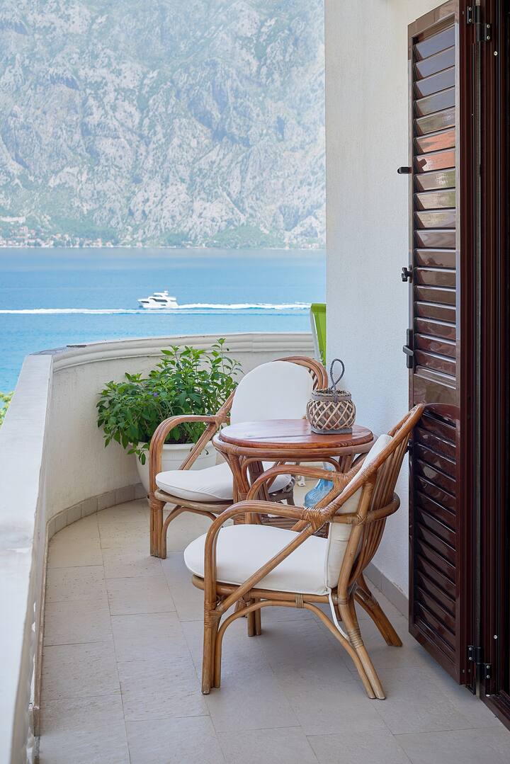 Balcony with rattan furniture and a view of the Bay of Kotor, apartment in Prčanj, Montenegro.