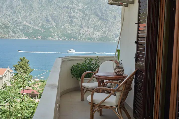 Balcony with wicker furniture and panoramic views of the Bay of Kotor and the mountains in Prčanj, Montenegro.
