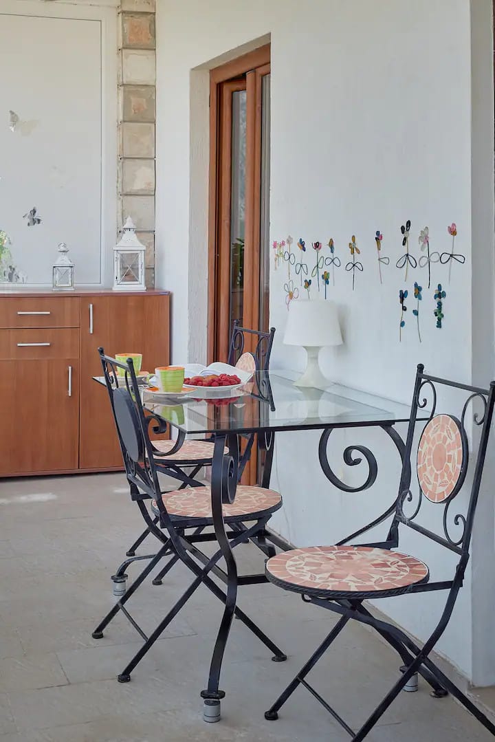 Cozy balcony with wrought-iron furniture and mosaic decor in an apartment, Prčanj, Montenegro. A table with breakfast on the terrace.