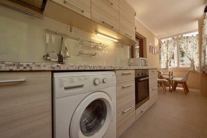 Kitchen in an apartment in Prčanj, Montenegro: light-colored cabinets, built-in appliances, washing machine, and dining area.