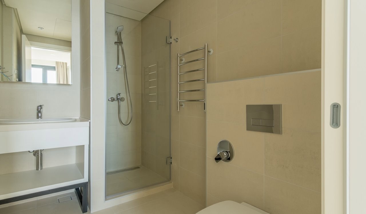 Modern bathroom with a shower cabin in an apartment in Bečići, Montenegro: beige tiles and fixtures.