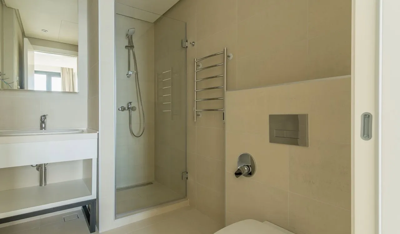 Modern bathroom featuring a glass shower enclosure, floating sink vanity, heated towel rail, and toilet.