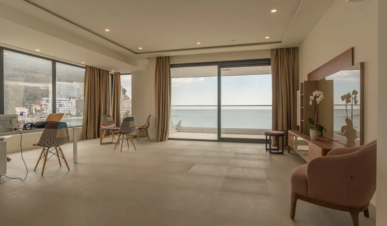 Bright room with sea view, pink armchair, desk with laptop, and large windows.