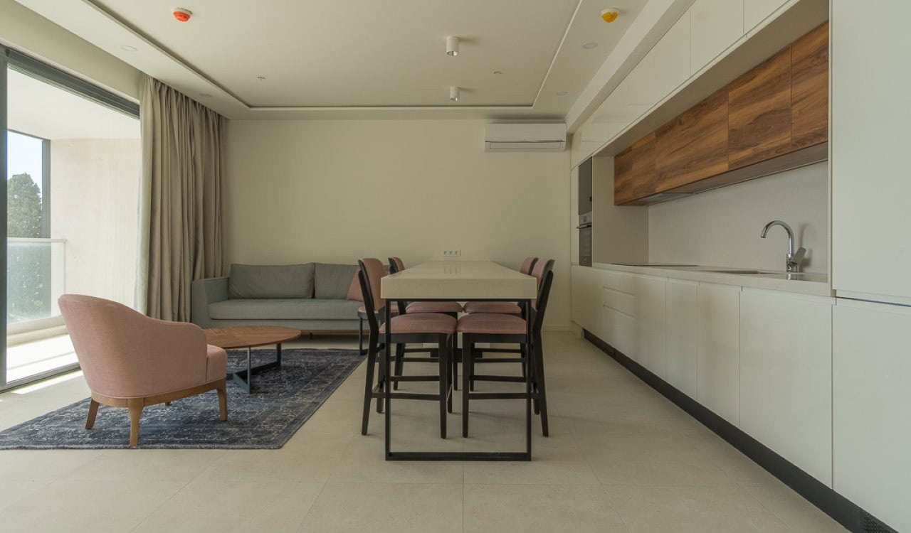 Modern living room with kitchen in an apartment in Becici, Montenegro: bright interior, soft furniture, and a terrace.