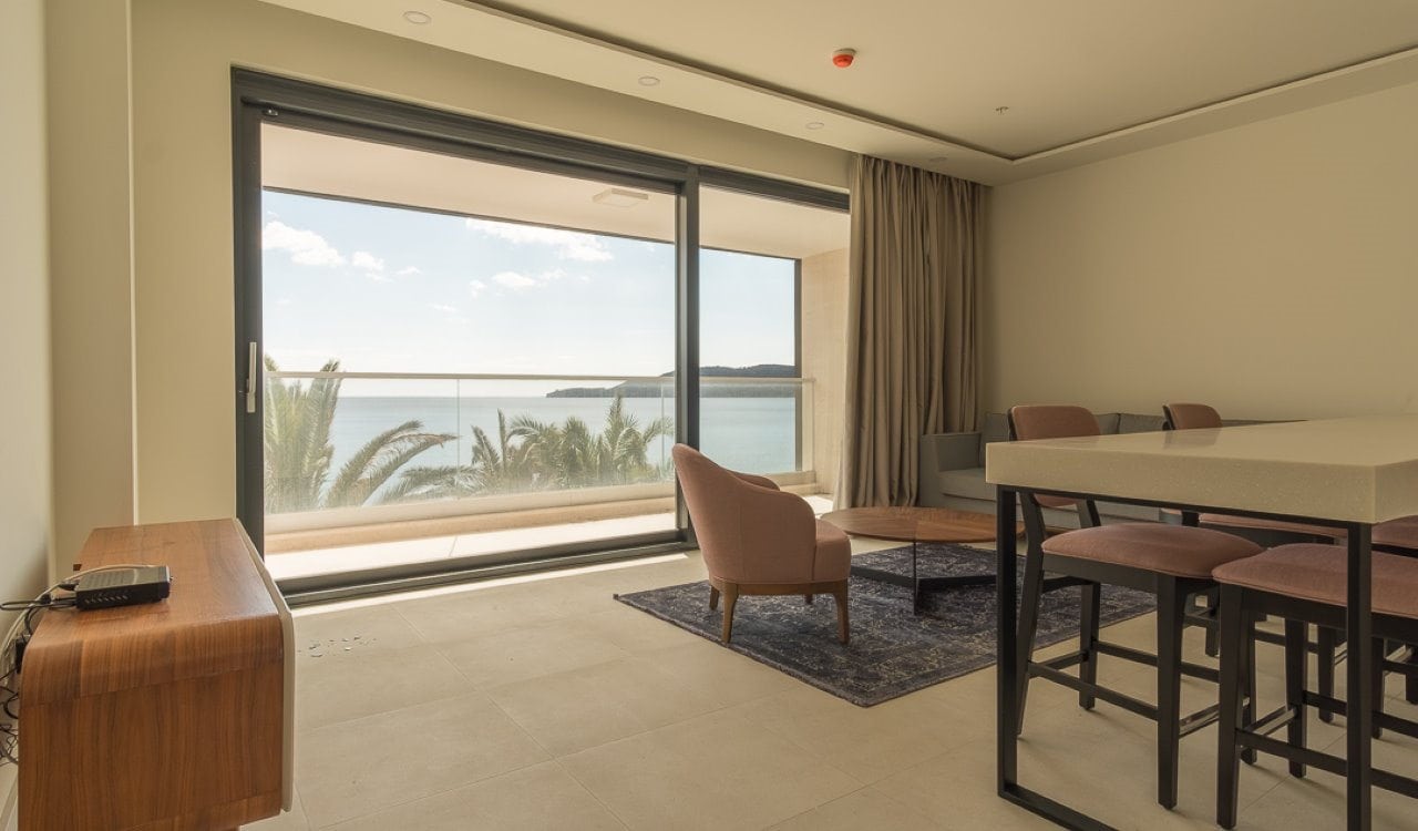 Living room in an apartment in Bečići, Montenegro: panoramic windows with sea view, modern furniture, and a terrace.