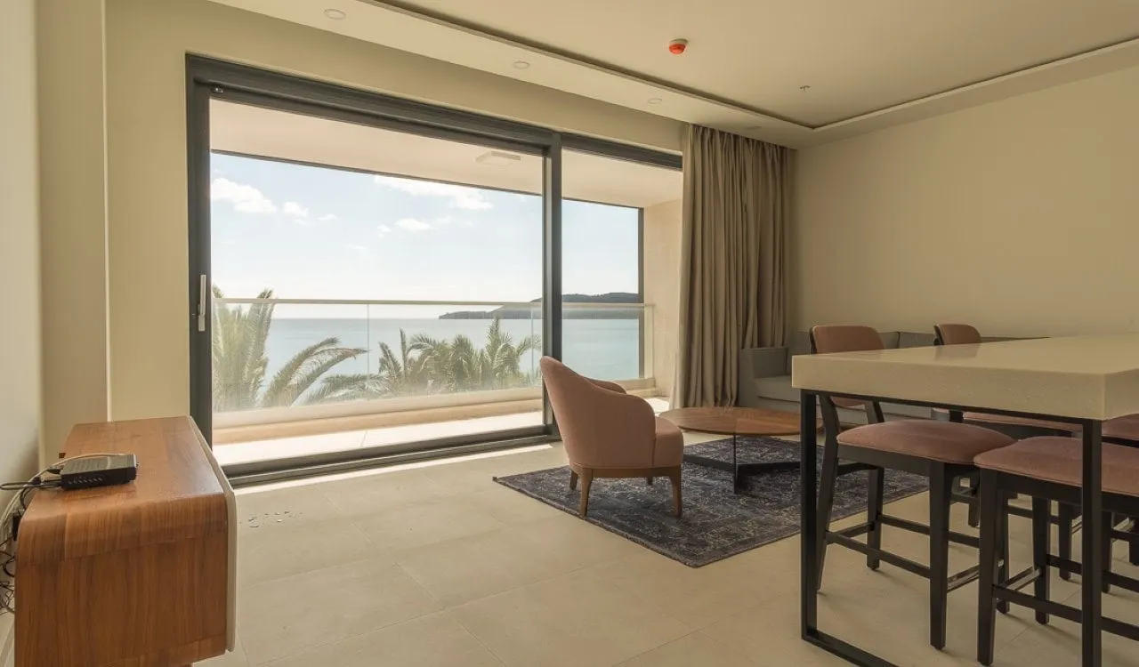 Living room with sofa, armchair, and bar counter opening to a balcony with sea view.
