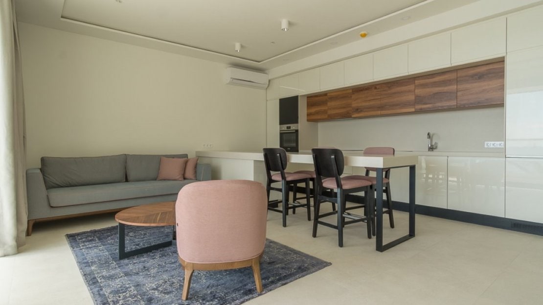 Modern living room with kitchen in an apartment in Bečići, Montenegro: stylish furniture, dining area, and bright interior.