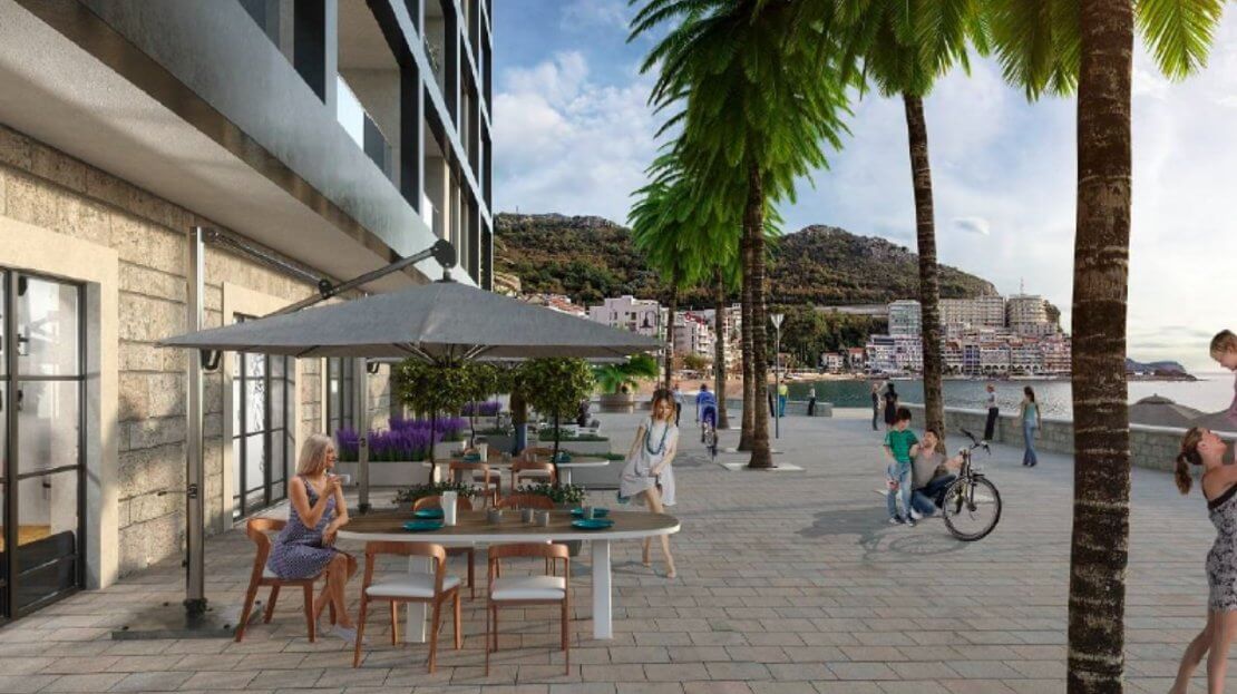 Summer terrace of a café by an upscale residential complex in Bečići, Montenegro: tables, umbrellas, and a view of the promenade and the sea.