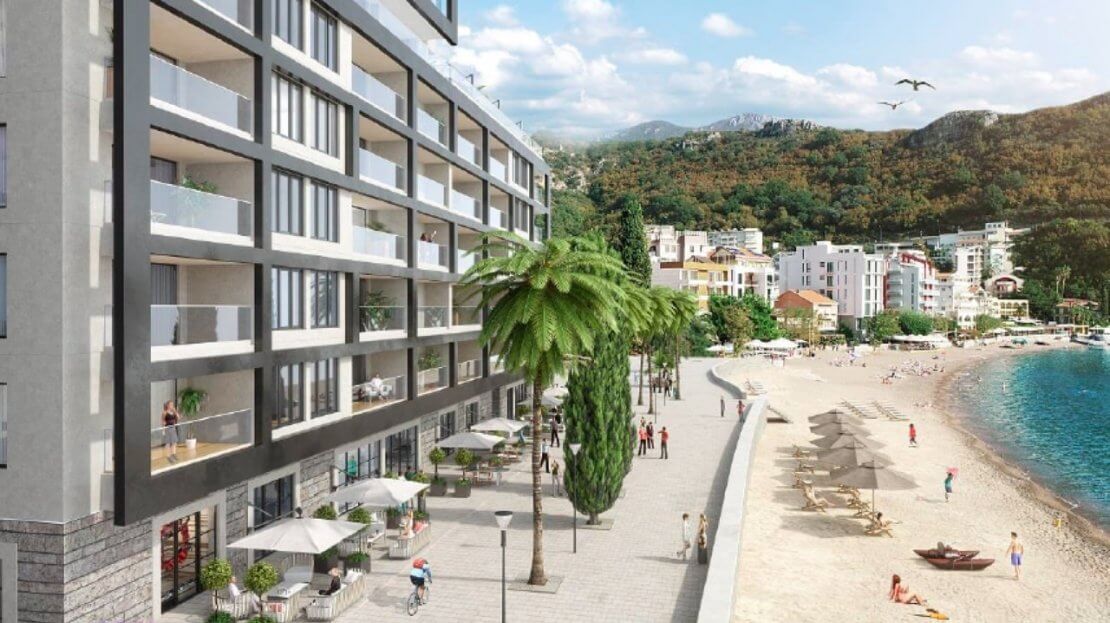 Modern residential complex by the sea in Bečići, Montenegro: view of the building with terraces, the promenade, and the sandy beach.