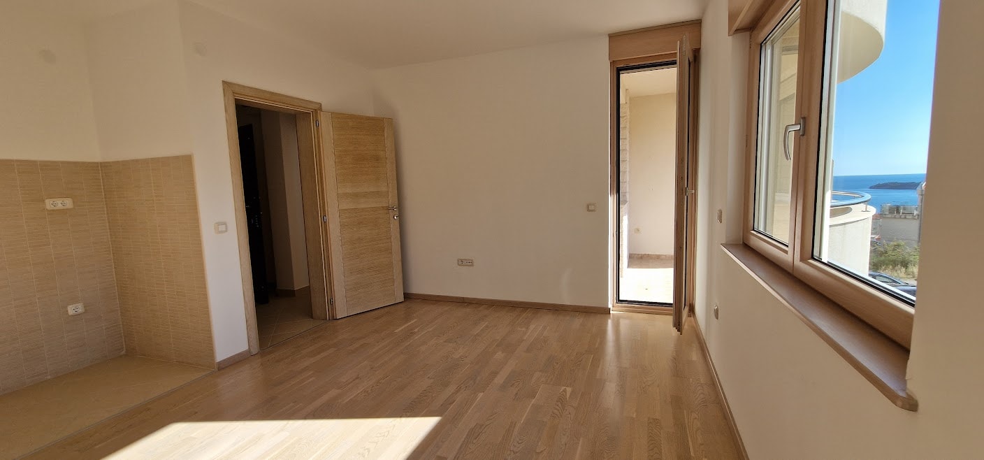 Bright living room with parquet flooring and access to the balcony in an apartment in Bečići, Montenegro, with panoramic sea views.